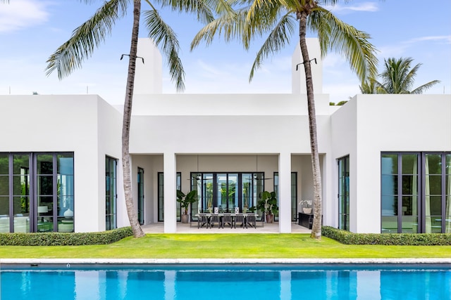 rear view of property featuring a patio and a lawn