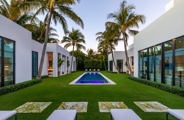 pool at dusk featuring a lawn