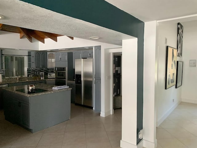 kitchen with tasteful backsplash, appliances with stainless steel finishes, dark stone counters, light tile patterned flooring, and gray cabinets