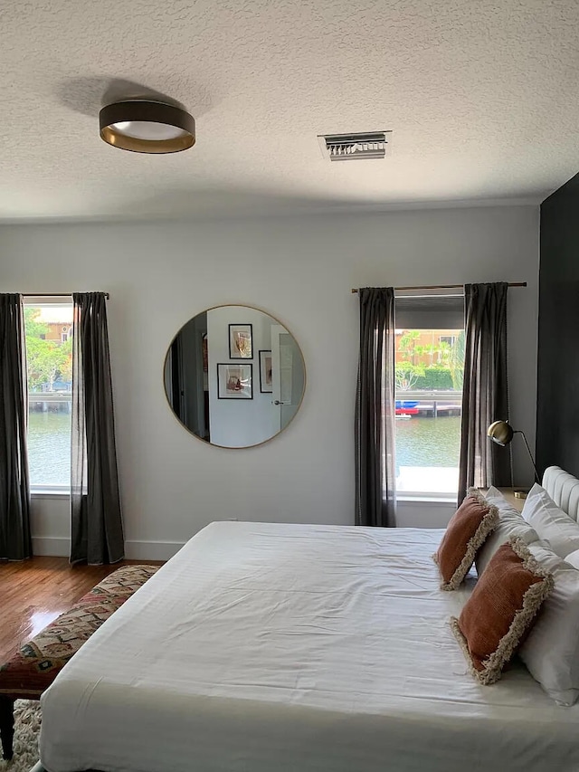 bedroom with a textured ceiling and wood-type flooring