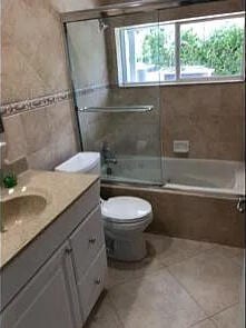 full bathroom featuring combined bath / shower with glass door, toilet, tile patterned floors, tile walls, and vanity