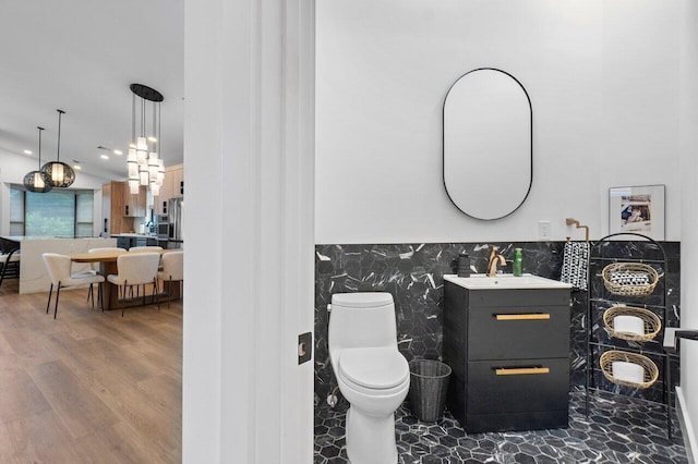 bathroom featuring toilet, hardwood / wood-style floors, vanity, and tile walls