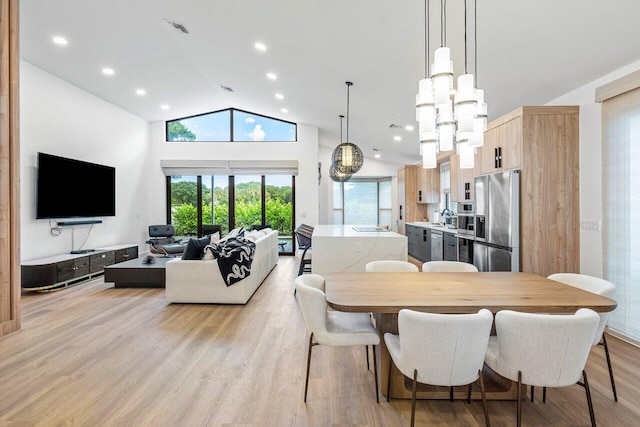 dining space with light hardwood / wood-style flooring, high vaulted ceiling, sink, and a notable chandelier