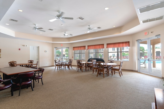 carpeted dining room featuring french doors, a tray ceiling, and a healthy amount of sunlight