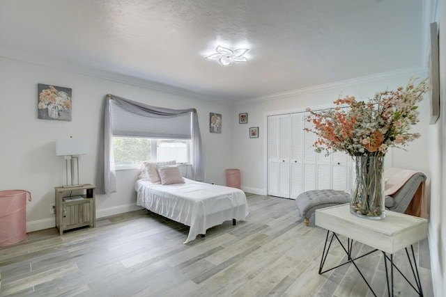 bedroom with light wood-type flooring, a closet, and crown molding