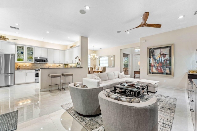 living room with ceiling fan with notable chandelier and a textured ceiling