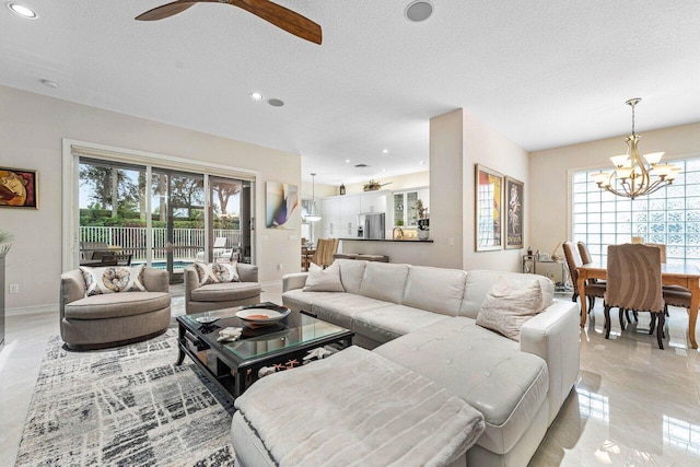 tiled living room with a wealth of natural light, ceiling fan with notable chandelier, and a textured ceiling