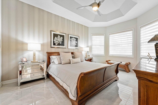 bedroom with a textured ceiling, a raised ceiling, multiple windows, and ceiling fan