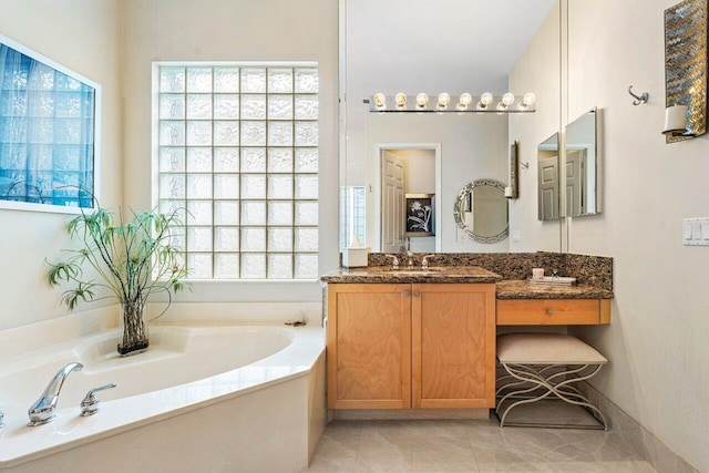 bathroom featuring vanity, a wealth of natural light, a washtub, and tile patterned floors