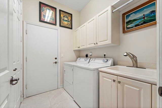 laundry area featuring light tile patterned flooring, a textured ceiling, cabinets, sink, and washer and dryer