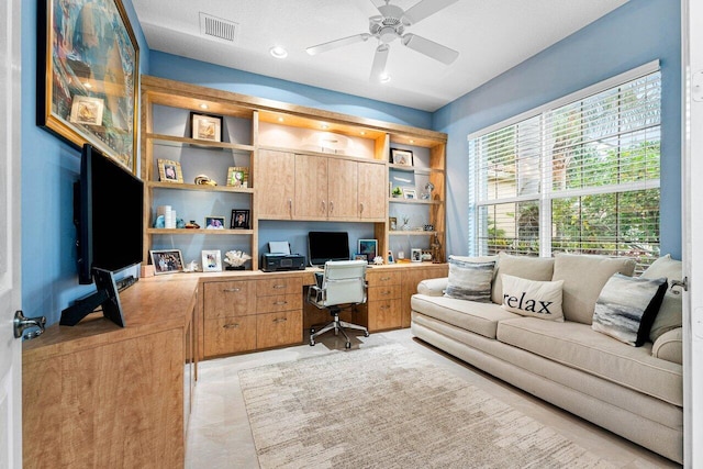 tiled office with built in desk, ceiling fan, and a textured ceiling