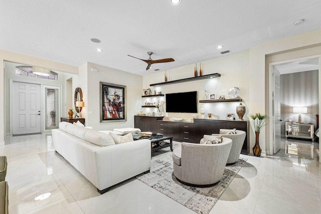 living room featuring ceiling fan and a textured ceiling