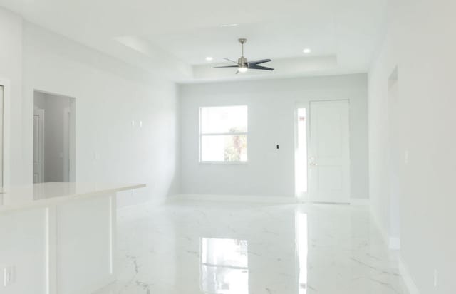 interior space with ceiling fan and a raised ceiling