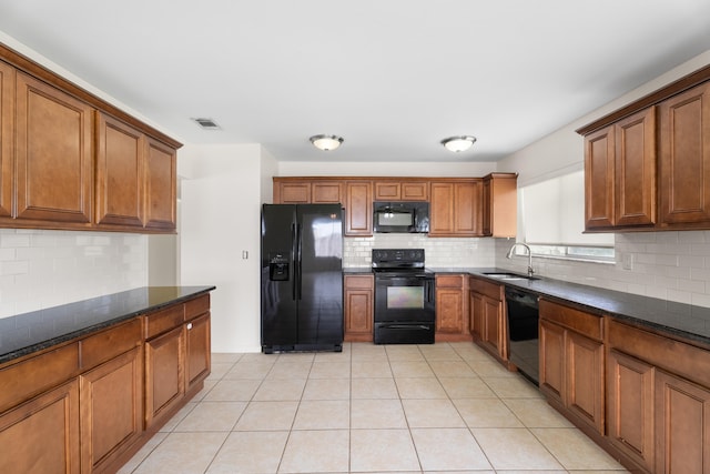 kitchen featuring tasteful backsplash, black appliances, sink, light tile patterned flooring, and dark stone countertops