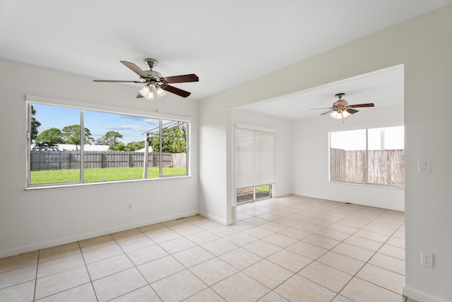 tiled empty room featuring ceiling fan and a wealth of natural light