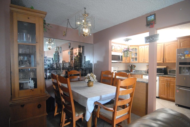 dining room featuring light tile patterned flooring, a textured ceiling, a chandelier, and sink