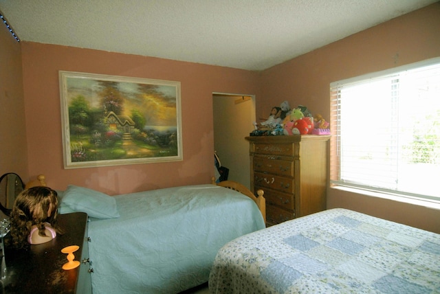 bedroom with a textured ceiling and multiple windows