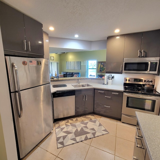 kitchen featuring sink, light tile patterned flooring, stainless steel appliances, and a textured ceiling