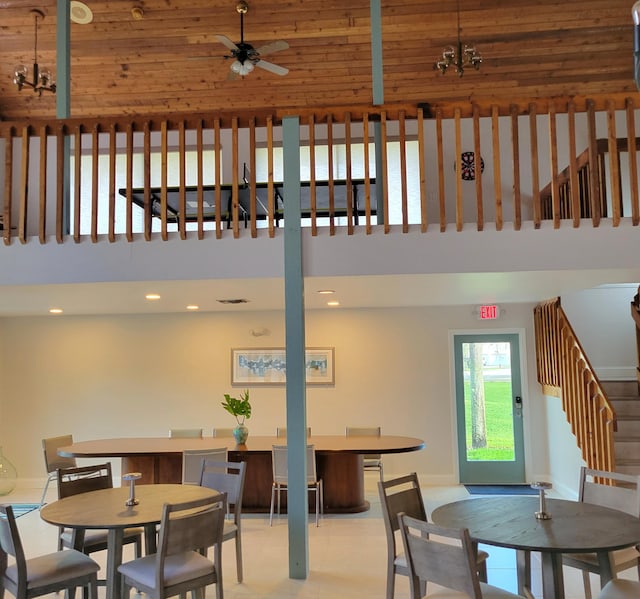 dining space with wood ceiling, a towering ceiling, and ceiling fan with notable chandelier