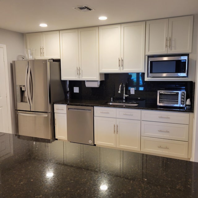 kitchen with sink, white cabinets, stainless steel appliances, and dark stone counters