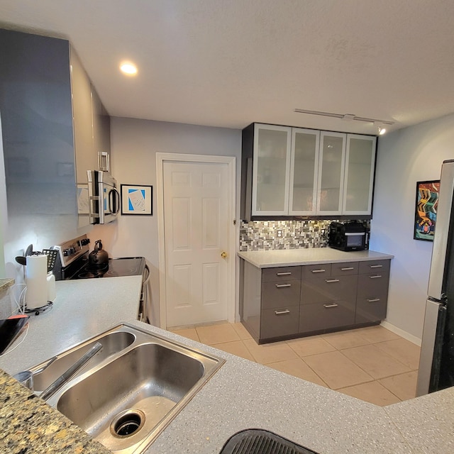 kitchen featuring light tile patterned floors, appliances with stainless steel finishes, backsplash, rail lighting, and sink