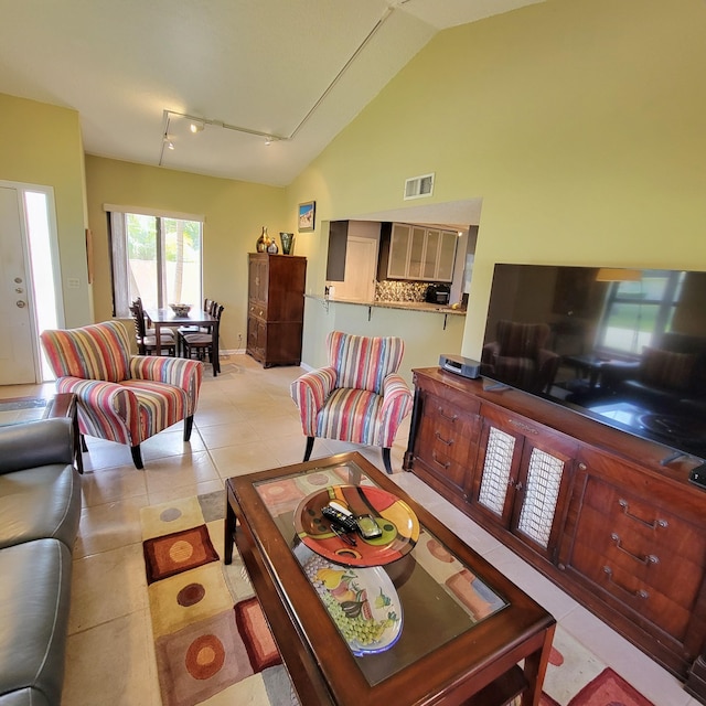 living room featuring track lighting, light tile patterned floors, and vaulted ceiling