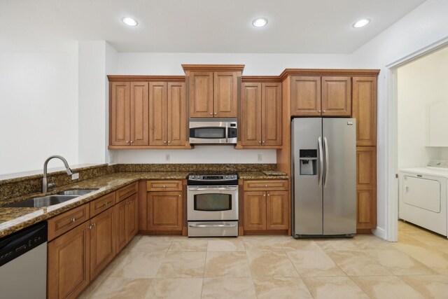 kitchen featuring separate washer and dryer, appliances with stainless steel finishes, dark stone countertops, sink, and light tile patterned floors