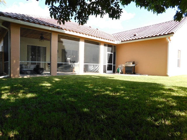 back of house with a yard, a sunroom, and ceiling fan