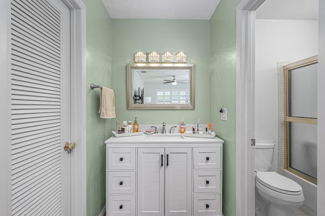 full bathroom with ceiling fan, a textured ceiling, toilet, shower / bath combination with glass door, and vanity