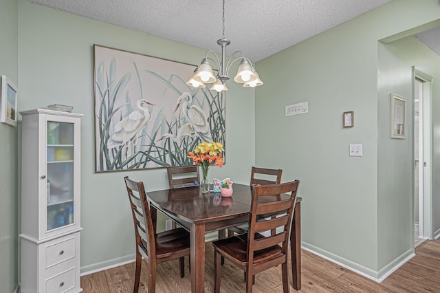 dining space with hardwood / wood-style floors, a textured ceiling, and a notable chandelier