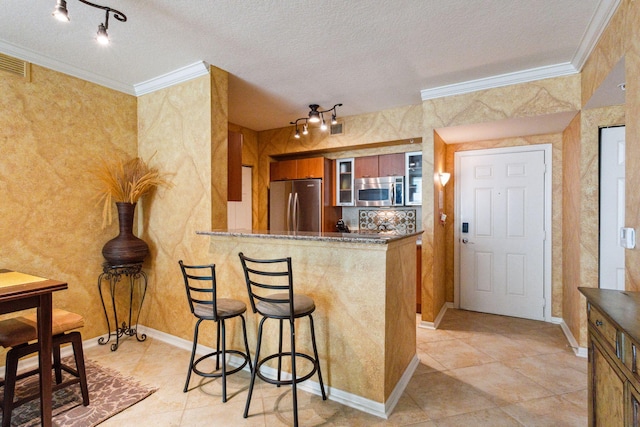 kitchen featuring kitchen peninsula, a breakfast bar, crown molding, appliances with stainless steel finishes, and a textured ceiling