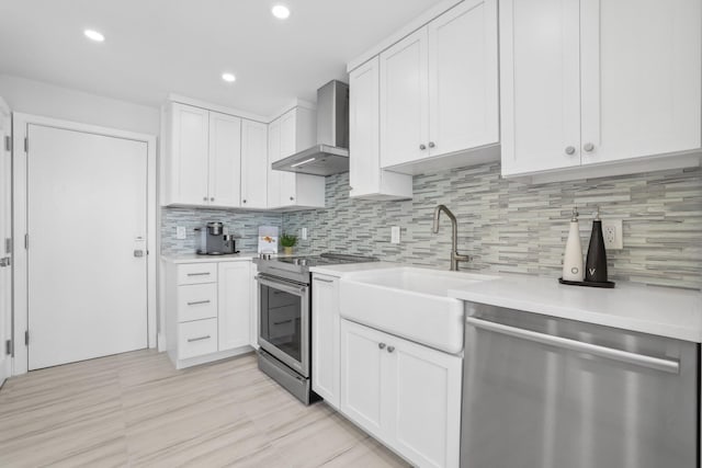 kitchen with white cabinetry, sink, appliances with stainless steel finishes, wall chimney exhaust hood, and backsplash