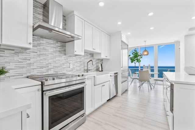 kitchen featuring stainless steel appliances, backsplash, pendant lighting, a water view, and wall chimney exhaust hood