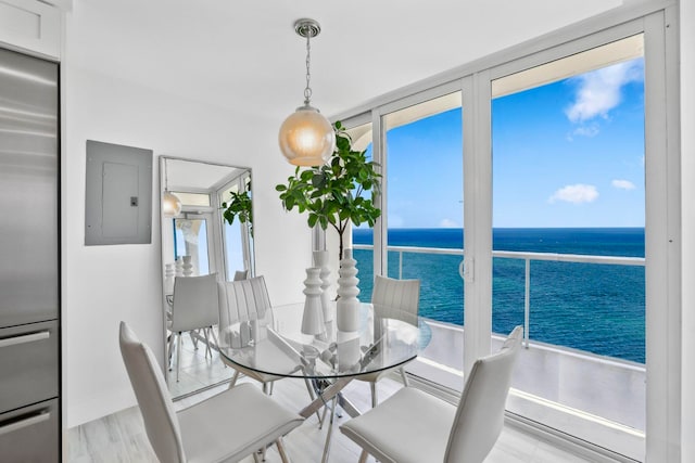 dining space with electric panel, a water view, and light wood-type flooring