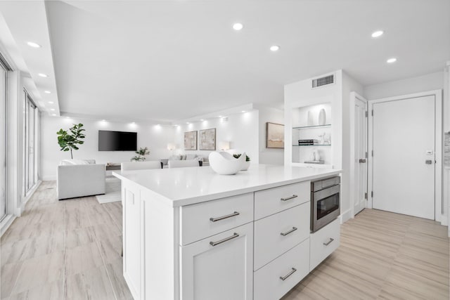 kitchen with built in shelves, a kitchen island, and white cabinets