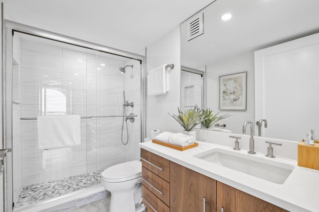 bathroom featuring vanity, toilet, and a shower with shower door