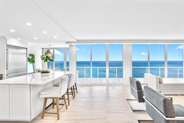 kitchen with white cabinetry, a wealth of natural light, stainless steel built in fridge, and a water view