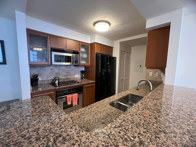 kitchen featuring tasteful backsplash, black appliances, sink, kitchen peninsula, and dark stone counters