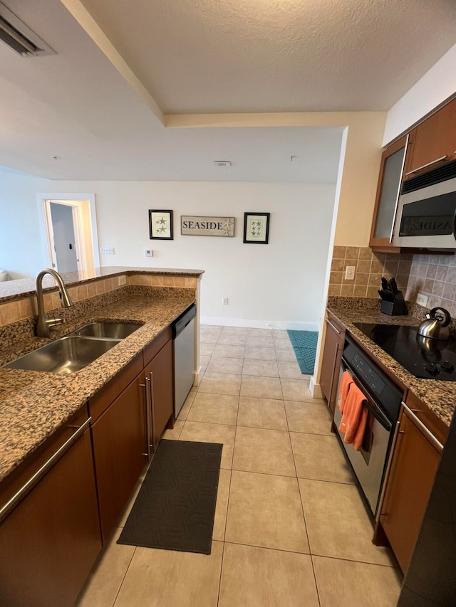 kitchen featuring decorative backsplash, light tile patterned floors, appliances with stainless steel finishes, a textured ceiling, and sink