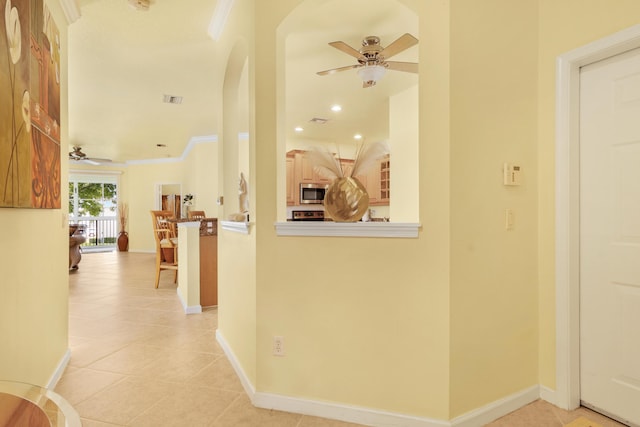 corridor featuring light tile patterned floors and crown molding