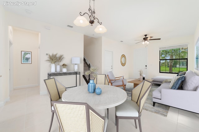 tiled dining space with ceiling fan with notable chandelier