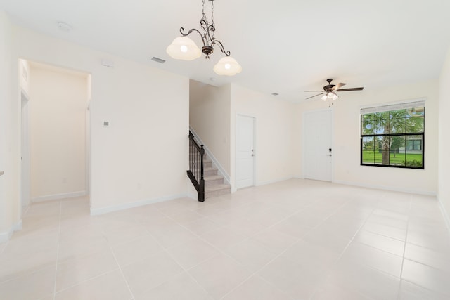 unfurnished room with light tile patterned flooring and ceiling fan with notable chandelier