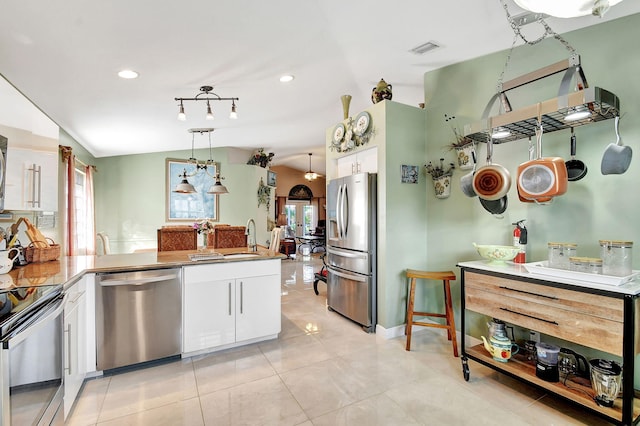 kitchen featuring hanging light fixtures, vaulted ceiling, light tile patterned floors, white cabinetry, and stainless steel appliances