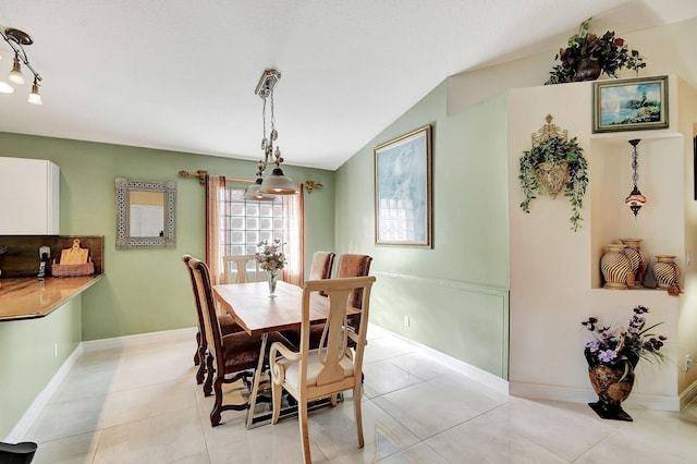 tiled dining space featuring vaulted ceiling