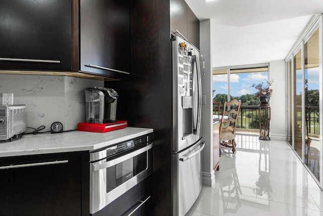 kitchen with backsplash, stainless steel appliances, light stone countertops, and light tile patterned floors