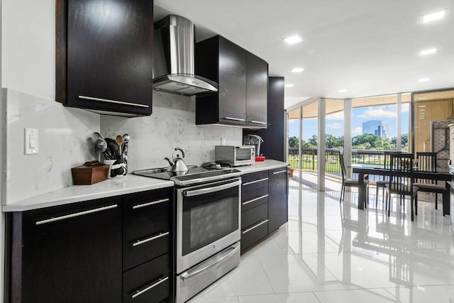 kitchen with wall chimney range hood, stainless steel electric stove, light tile patterned flooring, expansive windows, and tasteful backsplash