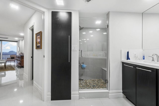 bathroom with a shower with door, vanity, and tile patterned flooring