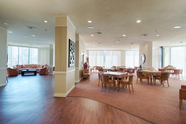 dining space featuring decorative columns, a textured ceiling, and hardwood / wood-style floors