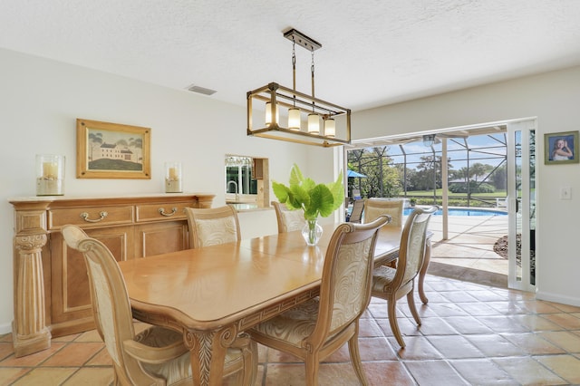 dining area featuring sink, light tile patterned floors, and a textured ceiling