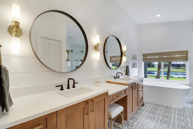 bathroom featuring tile patterned flooring, vanity, a tub to relax in, and vaulted ceiling